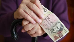 Důchodce drží českou bankovku 500 Kč a hůl v rukou, finanční pomoc seniorům
